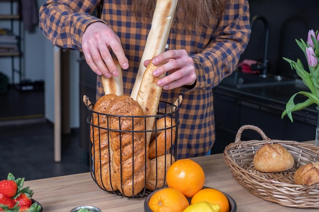 Wooden table with bread and fruit A man's hand is holding loaves of bread at the table