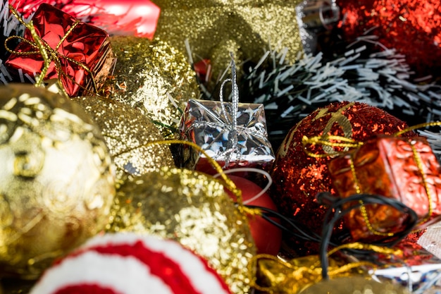 Wooden table with Christmas decorations. Red, silver and gold balls, gift boxes, lights, panettone, Christmas tree and others. Selective focus.