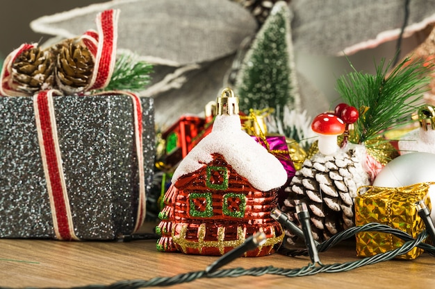 Wooden table with Christmas decorations. Red, silver and gold balls, gift boxes, lights, Santa Claus, Panettone, Christmas tree and others. Selective focus.