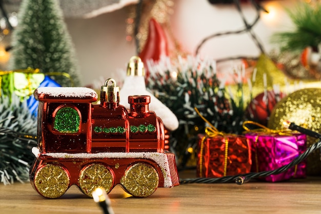 Wooden table with Christmas decorations. Red, silver and gold balls, gift boxes, lights, Santa Claus, Panettone, Christmas tree and others. Selective focus.