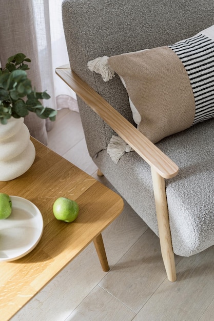 Wooden table with green apples close to comfy armchair