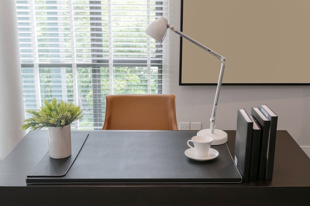 Wooden table with lamp and books in modern working room interior