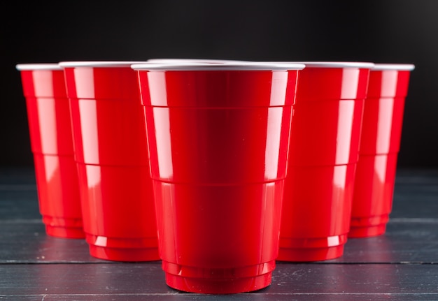 Wooden table with red cups and ball for beer pong