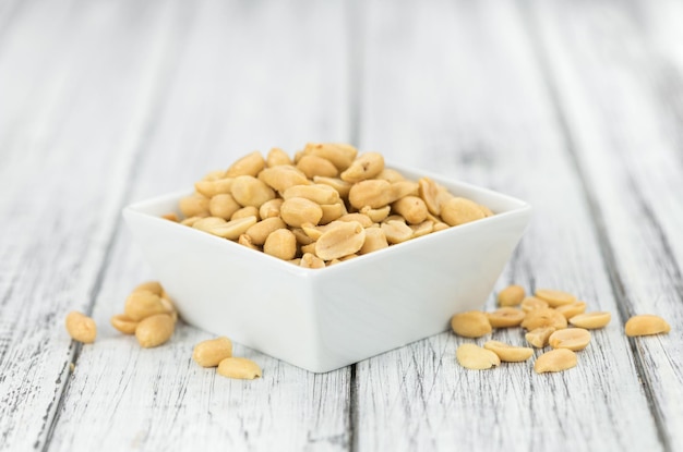 Wooden table with salted and roasted peanuts closeup shot