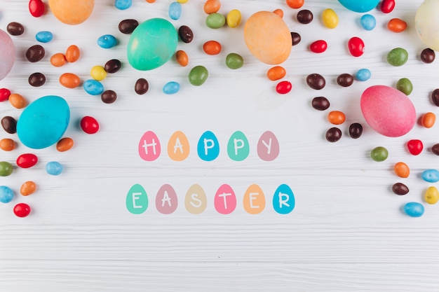 Wooden table with the text to Easter around eggs and candy