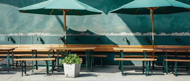 Photo wooden tables and benches under large green umbrellas in an outdoor cafe setting adjacent to a muted green wall adorned with plants creating a relaxing atmosphere