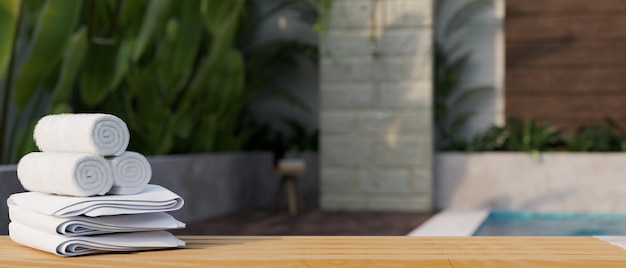 Wooden tabletop with towels and copy space over blurred home swimming pool in background