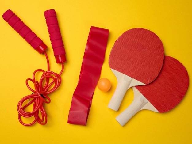 Wooden tennis racket for ping pong and a plastic ball on a yellow background