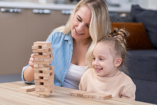 Wooden tower blocks game Mom and girl child enjoyinh playing together family playing board games