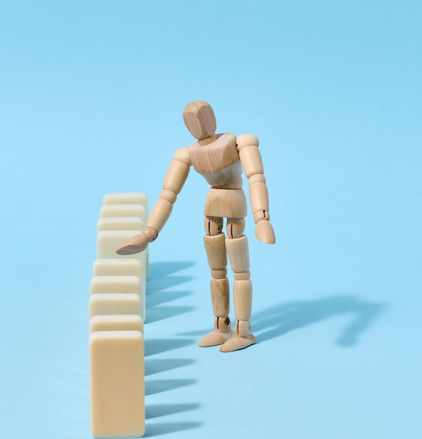 Wooden toy mannequin keeps dominoes from falling risk prevention concept