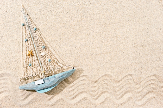 Wooden toy ship on sand, top view, copy space