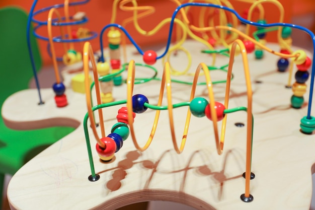 A wooden toy with colorful beads and a red, blue, and green ball.