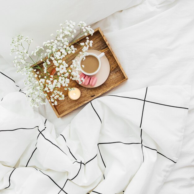 Wooden tray of coffee and candles on bed. Breakfast in bed. Hygge concept.