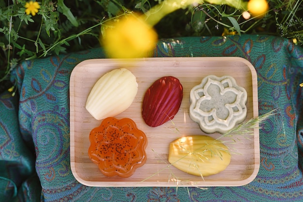 Wooden tray with different handmade handmade soaps on a meadow of flowers