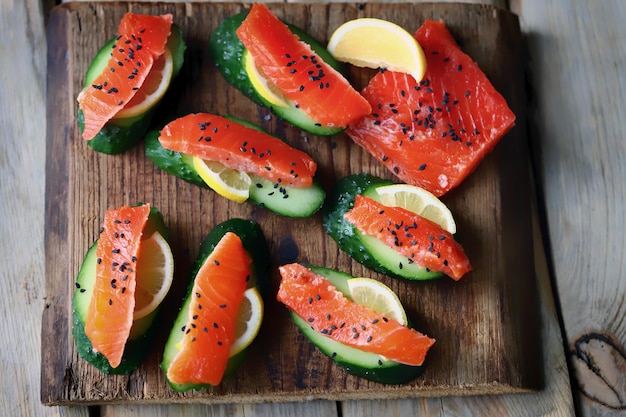 A wooden tray with salmon and cucumber slices on it