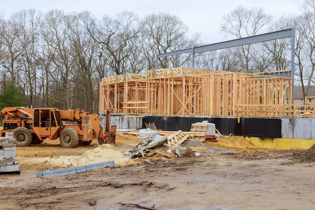 A wooden truss being lifted by a boom truck forklift in the building materials a stack of boards wood frame of a new home