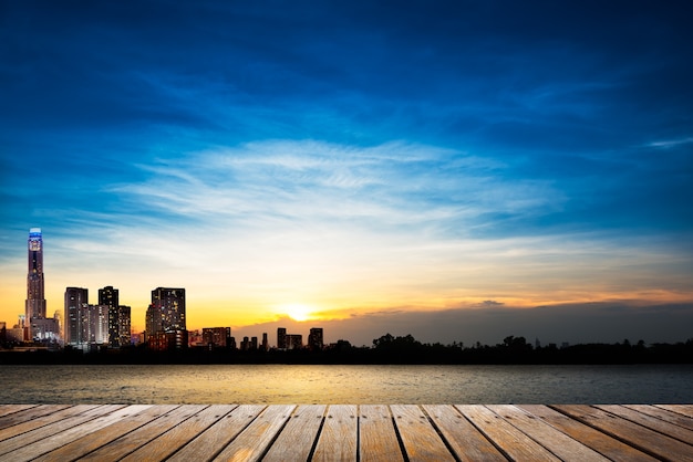 Wooden walkway at riverside on city and soft blue sky at sunset