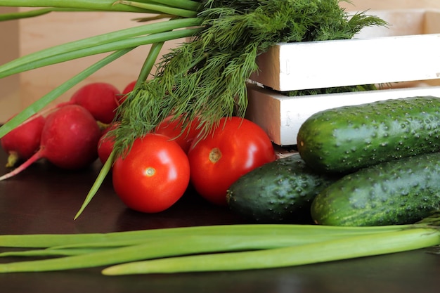 Wooden white basket with fresh vegetables A bunch of fresh vegetables in a basket on a wooden table