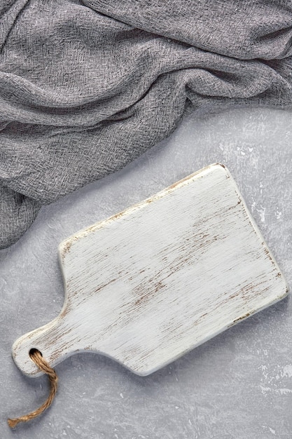 Wooden white cutting room and gray kitchen towel on a light gray concrete table Top view with copy space