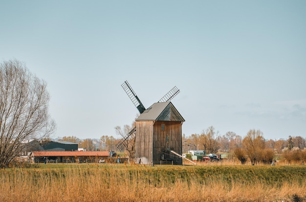 Wooden windmill stands on a coastline of a canal Spring landscape of a rural area in Poland