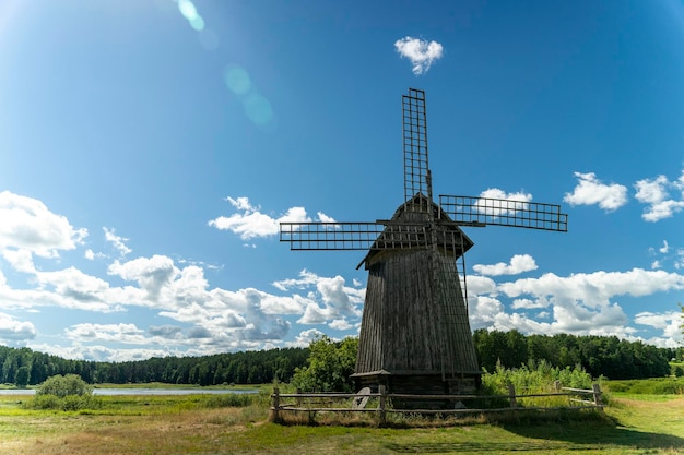 Wooden windmill in a summer field with a beautiful sunny sky forest