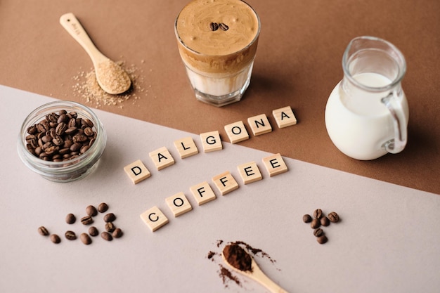 Wooden words dalgona coffee on a beige sheetbrown sugar coffee beans A glass of trendy fluffy Korean drink with whipped cream xD