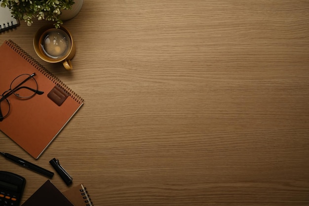 Wooden working desk with eyeglasses coffee cup and notebook Top view with copy space for text