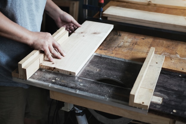 Woodworking practitioners use saw blades to cut wood pieces to assemble and build wooden tables for