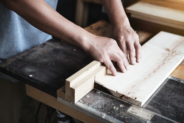 Woodworking practitioners use saw blades to cut wood pieces to assemble and build wooden tables for