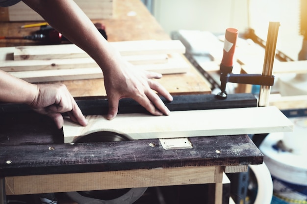 Woodworking practitioners use saw blades to cut wood pieces to assemble and build wooden tables for