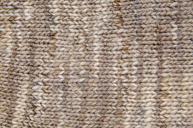 Wool scarf texture close up. Knitted jersey background with a relief pattern. Braids in machine knitting pattern