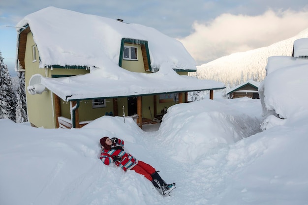 Wooman enjoys nature near an alpine house with white fluffy snow in the winter mountains