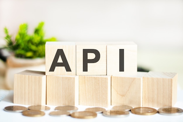 The word api on wood cubes, banknotes and calculator on the background.