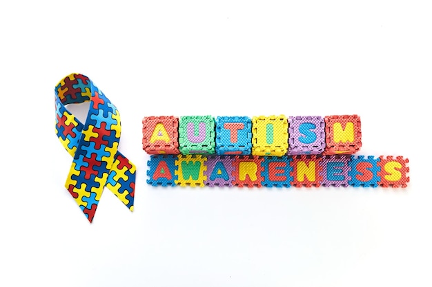 Word autism awareness day autism awareness ribbon and puzzle cubes on blue background