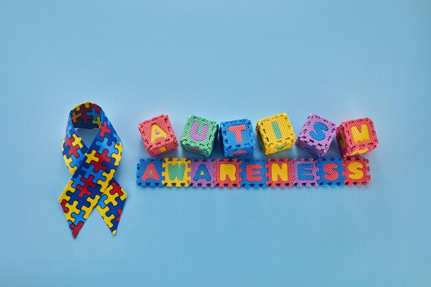 Word autism awareness day autism awareness ribbon and puzzle cubes on blue background