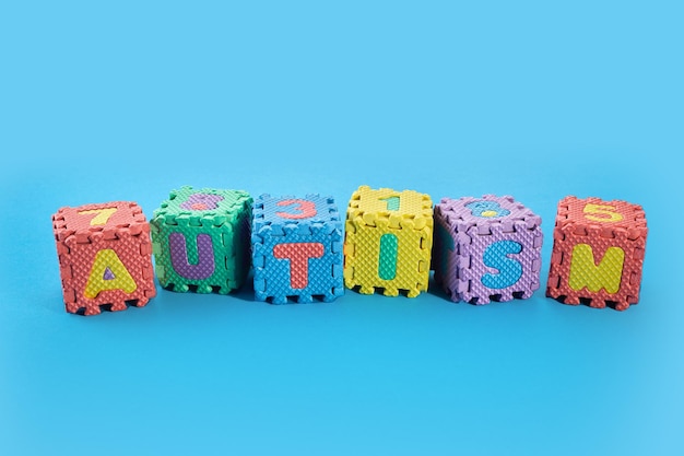 Word autism on puzzle cubes on blue background