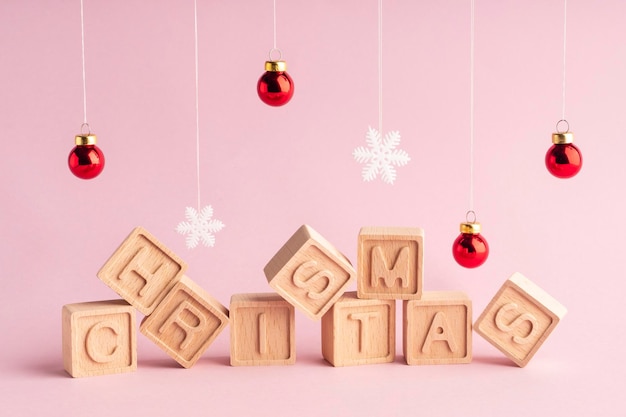 The word Christmas made up of wooden cubes on a pink background Snowflakes and Christmas balls Christmas card