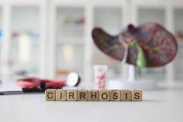 Photo word cirrhosis made of wooden blocks against model of liver