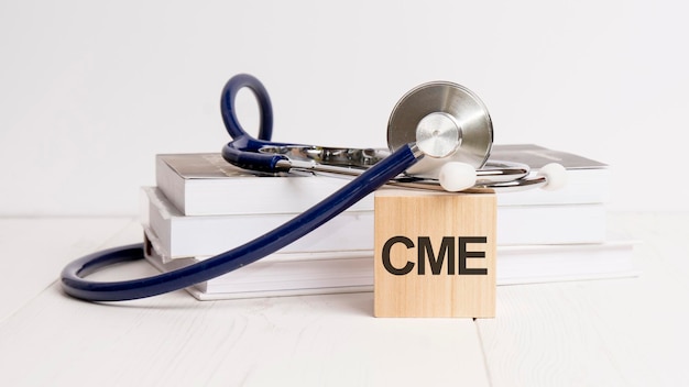 The word CME is written on wooden cube near a stethoscope on a white background CME short for Continuing Medical Education Medical concept