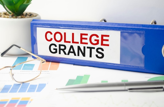 The word college GRANTS is written on a blue file folder next to documents