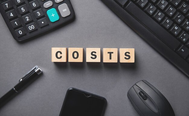 Photo word costs on wooden cubes and business objects.