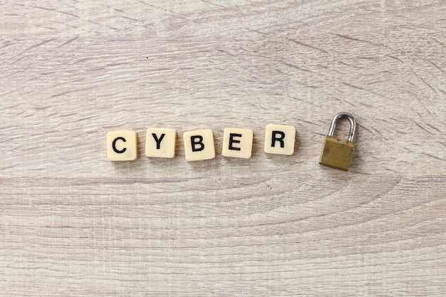 The word cyber formed  by alphabet square tiles with lock on wooden background.