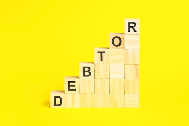 The word DEBTOR is written on a wooden cubes concept