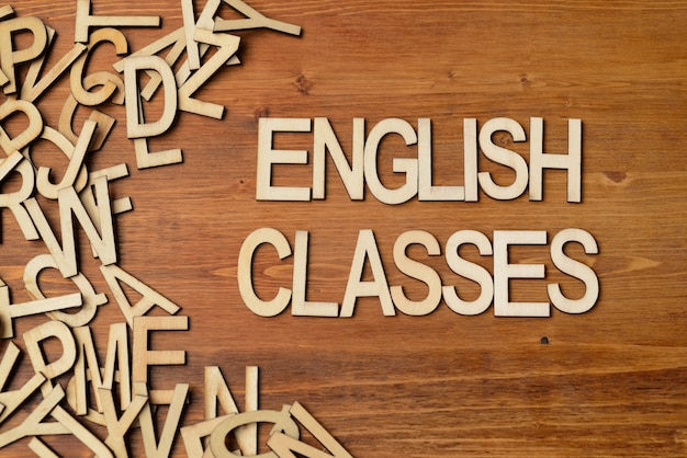 Word english classes made with wooden letters on the white plank table