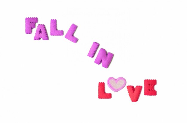 The word FALL IN LOVE spelled with alphabet biscuits and heart shaped marshmallow