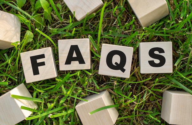 The word faqs is written on wooden cubes the blocks are located on green grass with sunlight