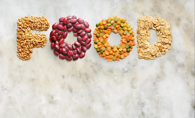 Word FOOD made of cereals on marble slab background