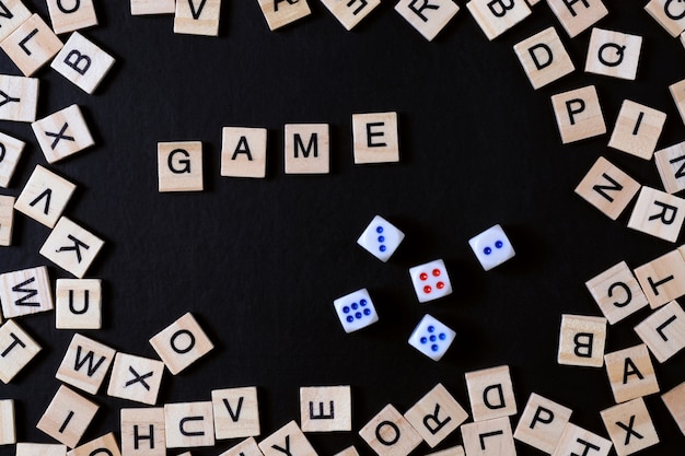 Word GAME with wooden letters on black Board with dice and letter in the circle