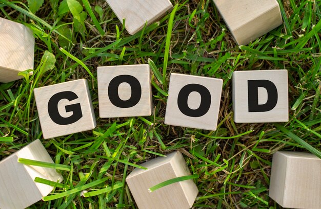 The word good is written on wooden cubes the blocks are located on green grass with sunlight