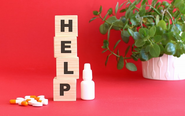 The word HELP is made of wooden cubes on a red surface with medical drugs. Medical concept.